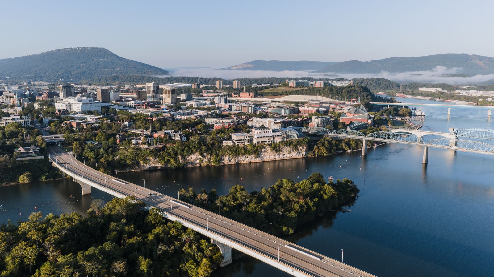 Aerial view of the Chattanooga skyline with bridges over the Tennessee River and mountains beyond